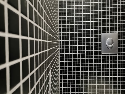 a black and white tiled bathroom with a toilet paper dispenser
