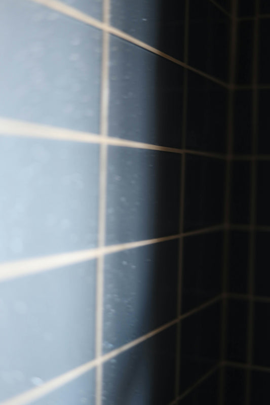 a close up of a bathroom wall with black tiles