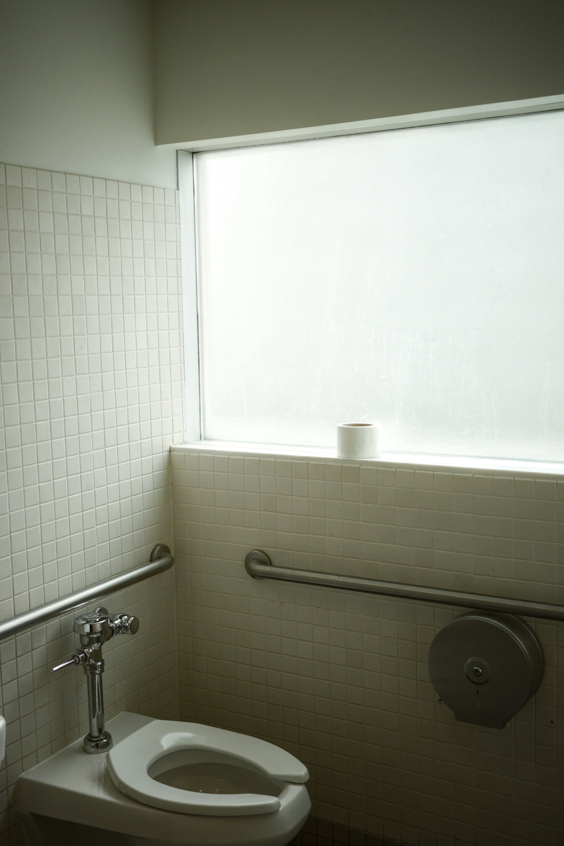 A white toilet sitting next to a window in a bathroom