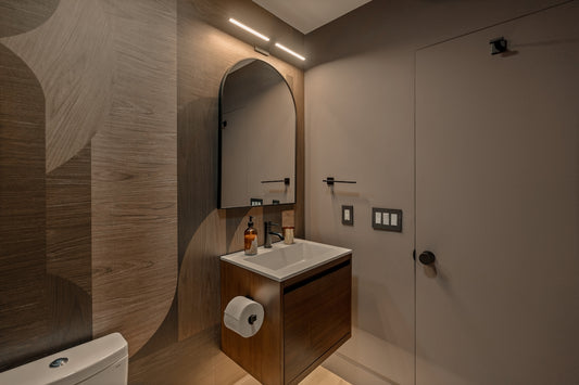 Modern bathroom with a wooden vanity and arched mirror.