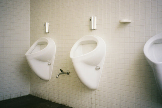 Two white urinals mounted on a tiled wall.