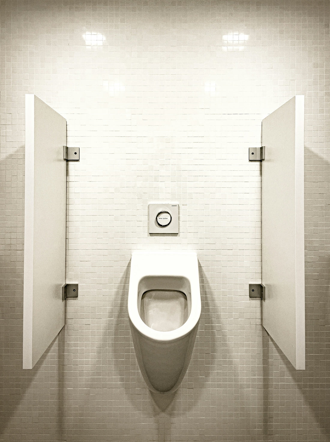 A white urinal with partition walls in a restroom