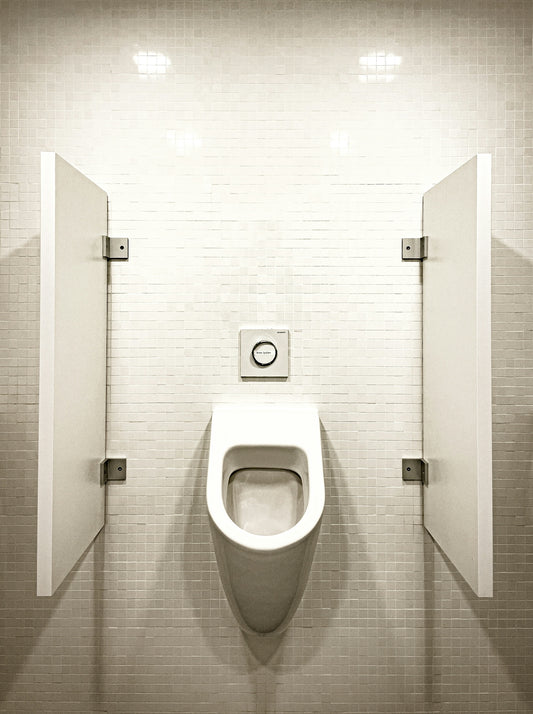 A white urinal with partition walls in a restroom