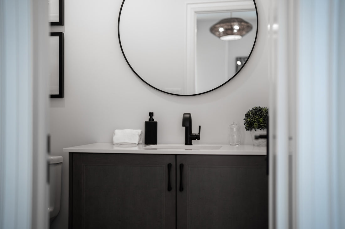 Modern bathroom vanity with a round mirror above.