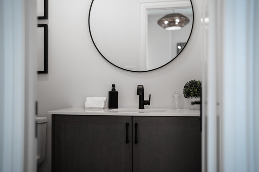 Modern bathroom vanity with a round mirror above.