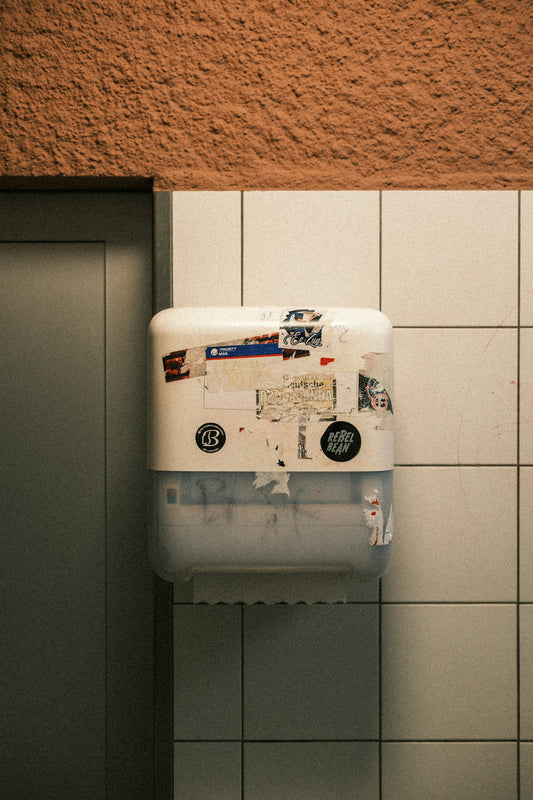 A white paper towel dispenser covered in stickers