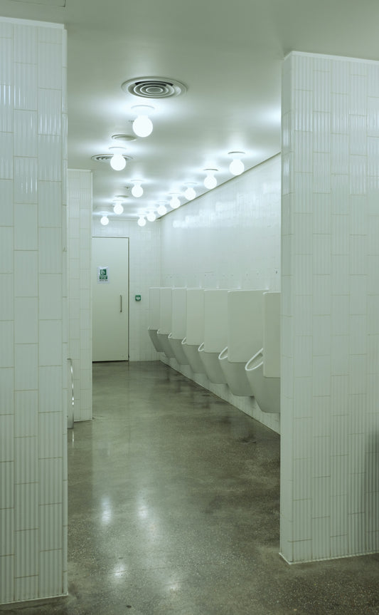 Modern public restroom with white urinals and bright lighting.