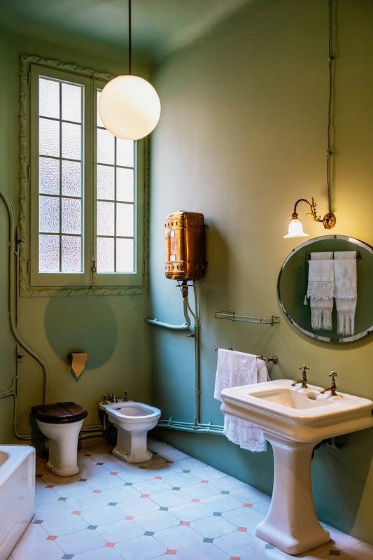 Vintage bathroom with green walls, a window, and classic fixtures.
