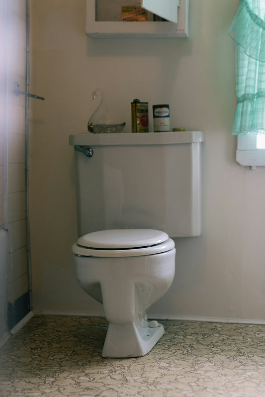 A white toilet in a bathroom with a green curtain.