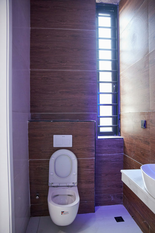 A modern bathroom with wood-look wall tiles, a white toilet, and a tall window